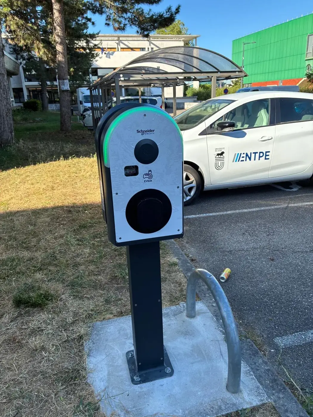 Borne de recharge Schneider sur pied installée sur le parking d'un établissement public